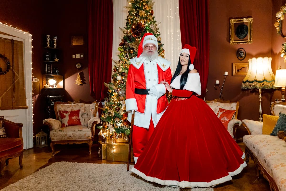 Moș Crăciun și Crăciunița în sufragerie, lângă bradul decorat